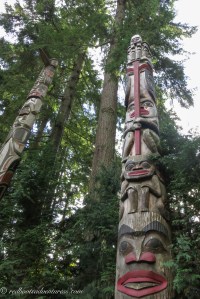 Two totem poles and tall trees